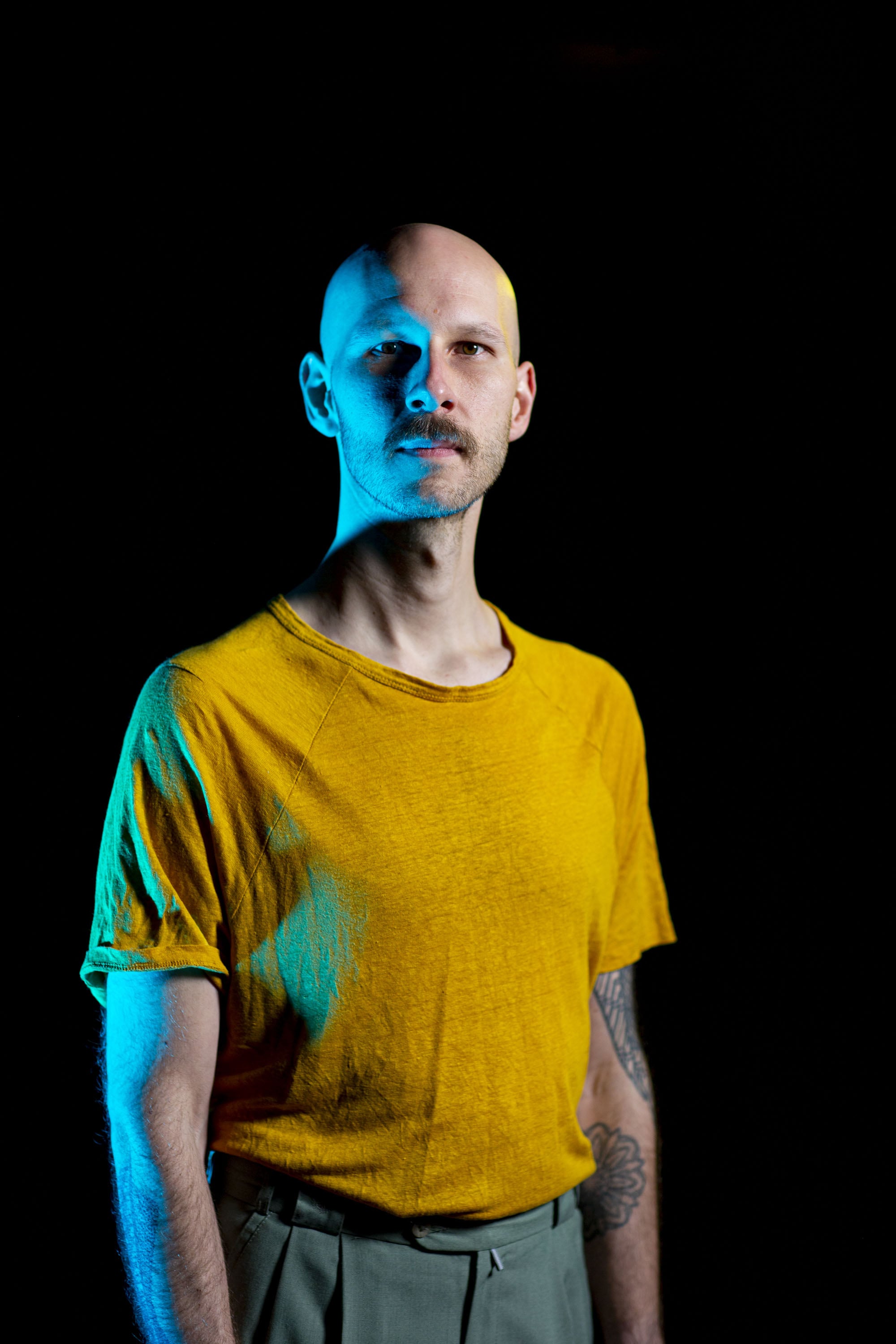 Studio Portrait of Timm Roller, wearing a yellow shirt in blue light.