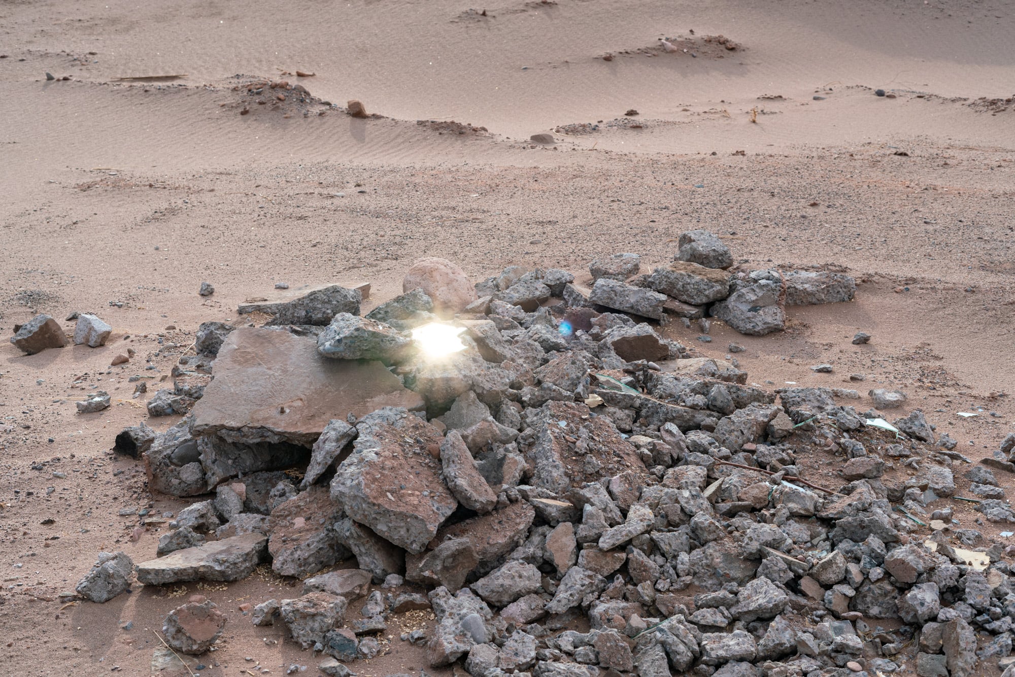 Photography of a pile of rubble with a flaring reflection in the center.